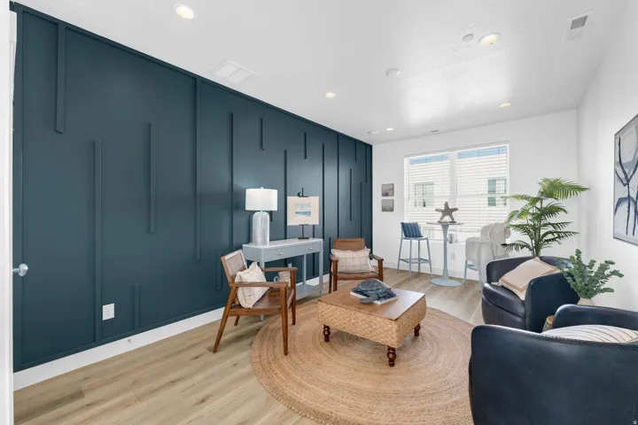 Living room with a decorative wall, light wood-style flooring, and recessed lighting