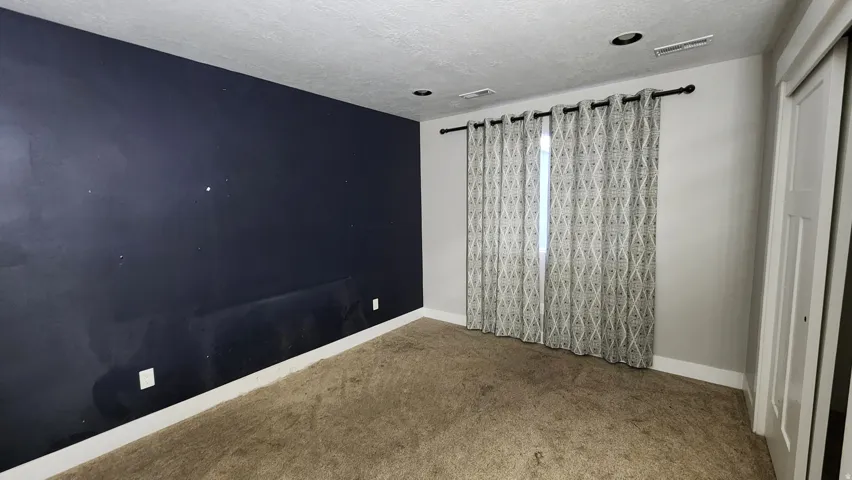 Empty room featuring carpet and a textured ceiling