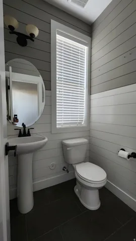 Bathroom featuring dark tile patterned flooring and wood walls