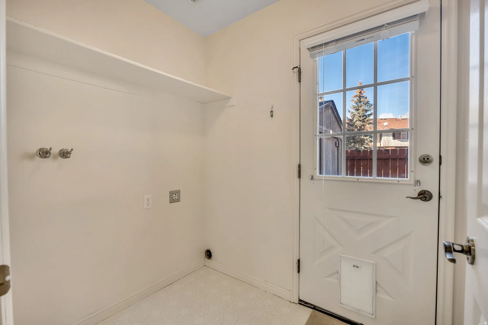 Laundry room with light flooring and hookup for an electric dryer