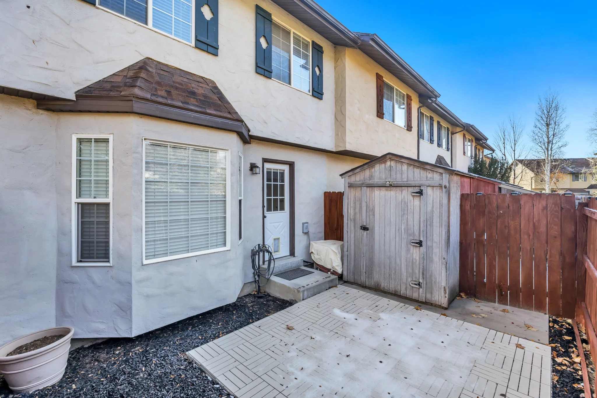 Back of property featuring a storage shed, stucco siding, a patio, and a fenced backyard