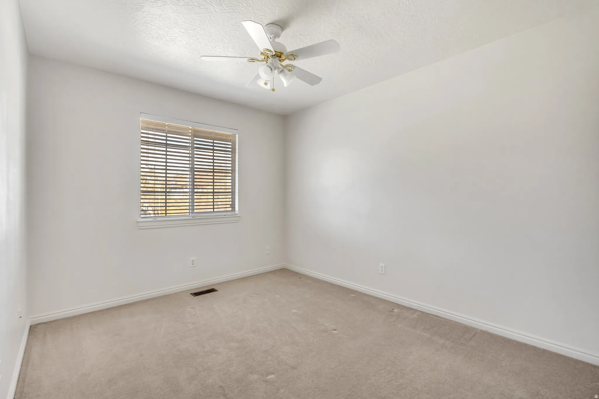 Carpeted spare room with a ceiling fan and a textured ceiling