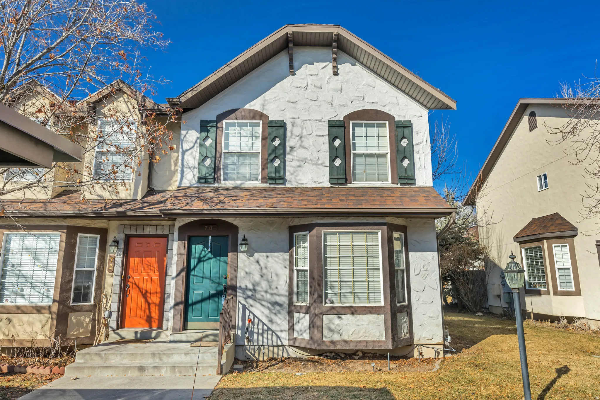 View of front facade with stucco siding, roof with shingles, and a front lawn