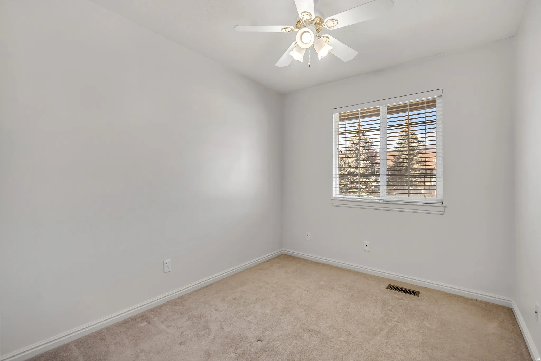 Carpeted spare room featuring a ceiling fan and baseboards