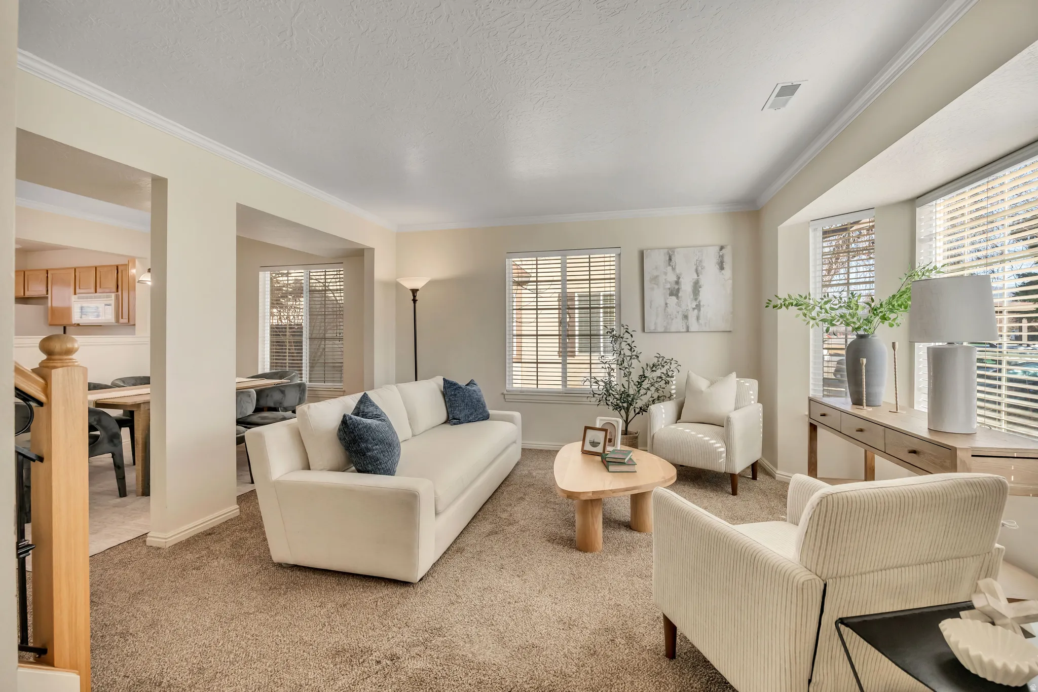 Living room featuring light colored carpet, ornamental molding, and a textured ceiling