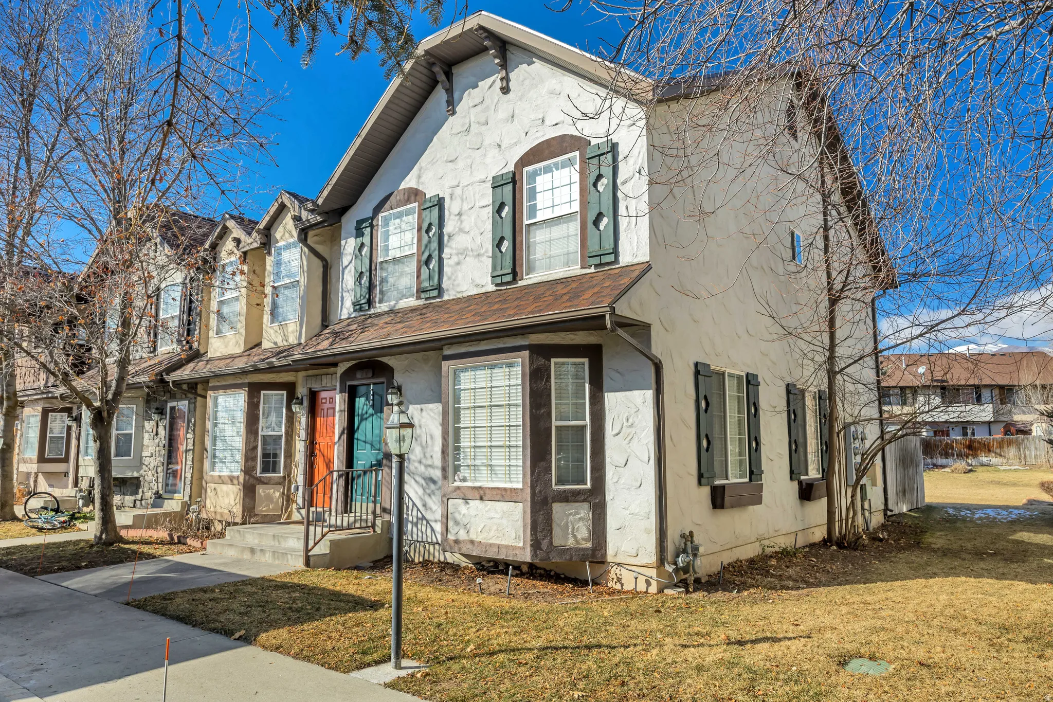 View of front facade with a front yard, stucco siding, and roof with shingles