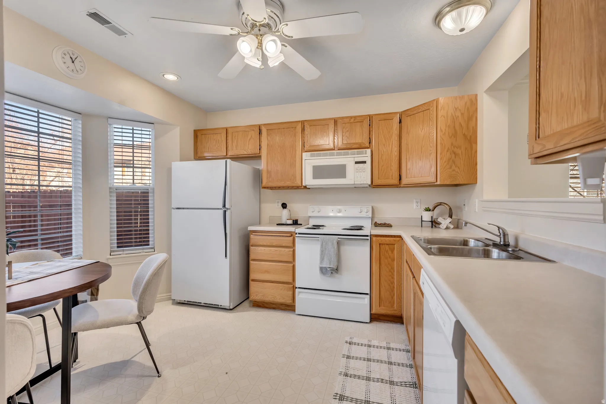 Kitchen featuring white appliances, light flooring, light countertops, a ceiling fan, and recessed lighting