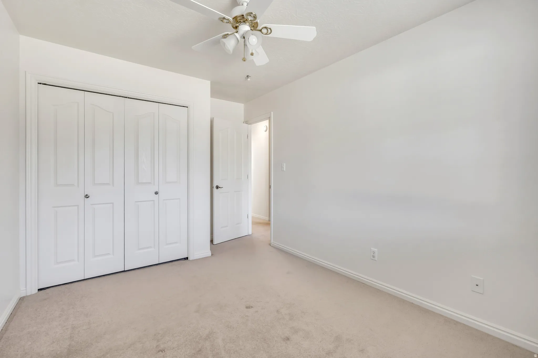 Unfurnished bedroom featuring carpet, a ceiling fan, and a closet