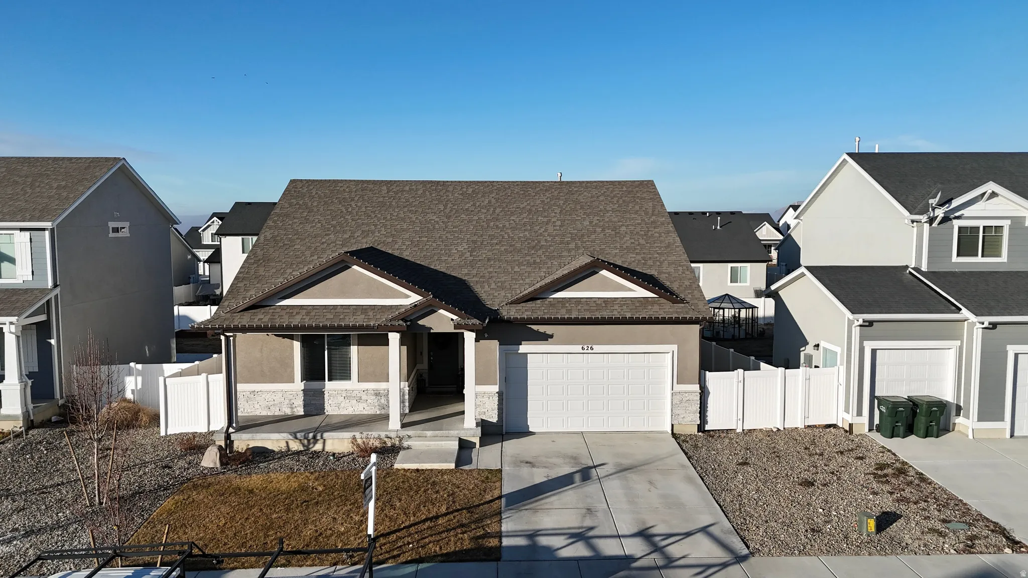 View of front of house with a residential view, concrete driveway, stone siding, stucco siding, and a garage