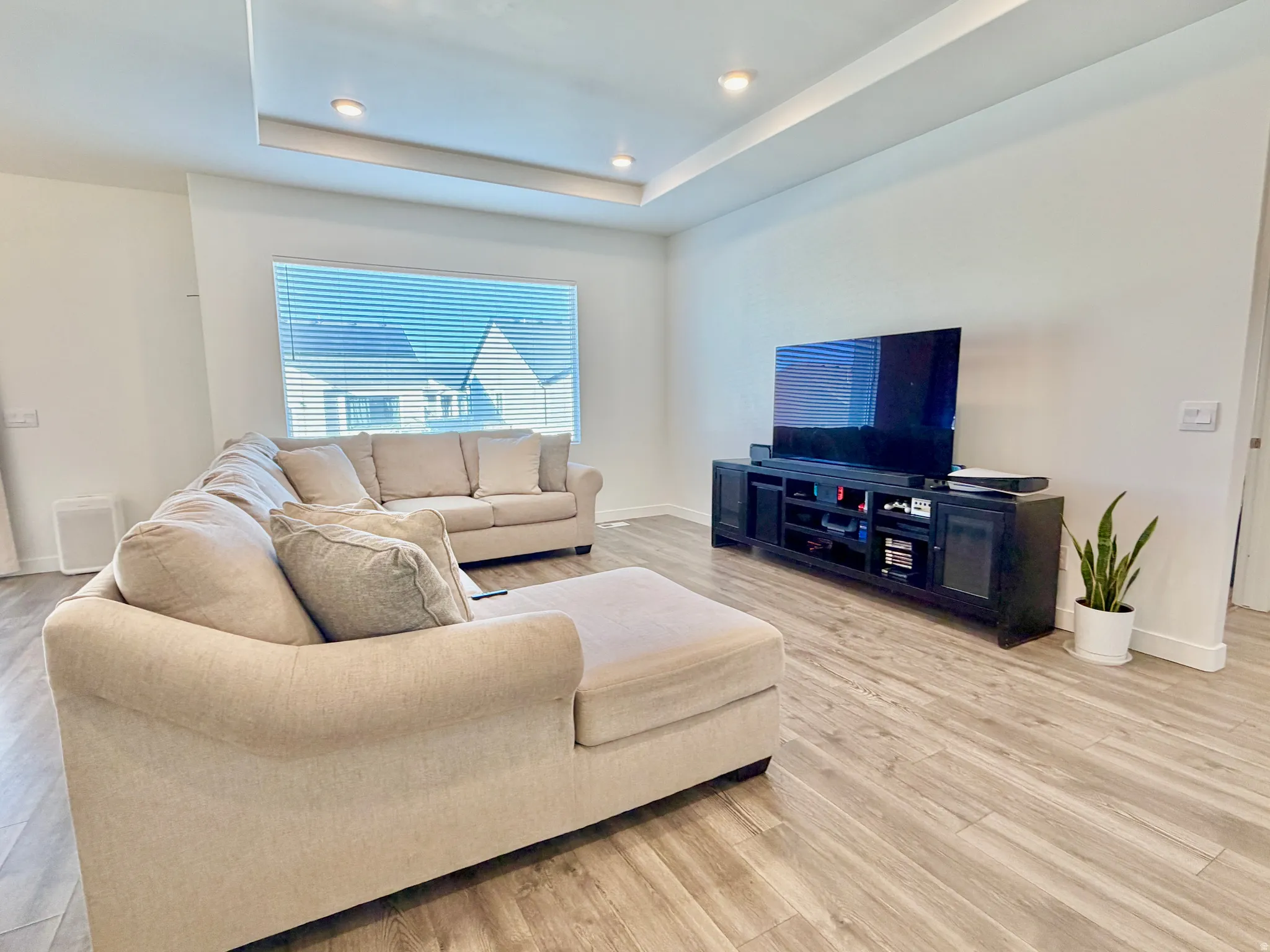 Living room featuring light wood-style floors, a raised ceiling, and recessed lighting