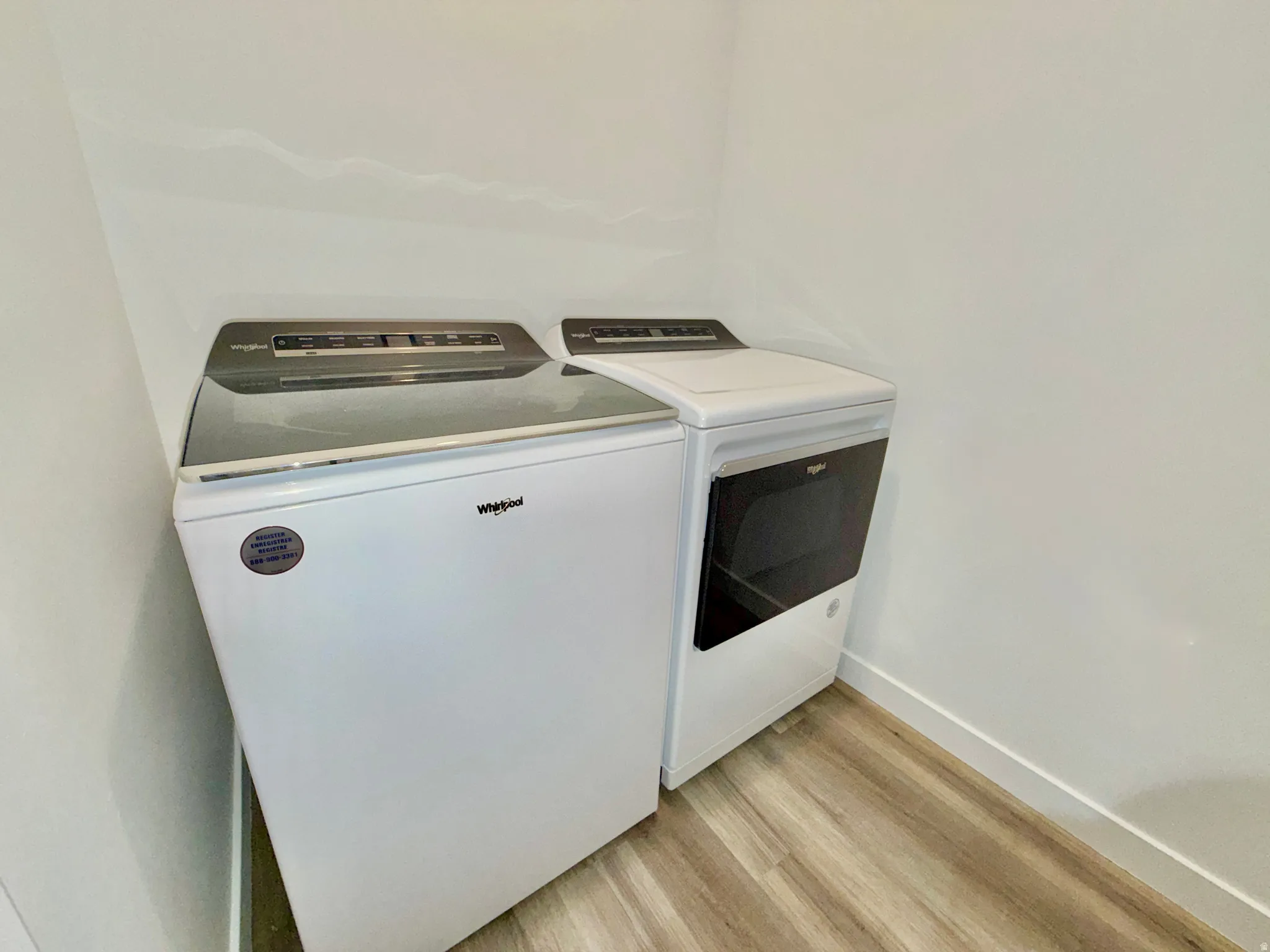 Washroom with independent washer and dryer and light wood-style flooring
