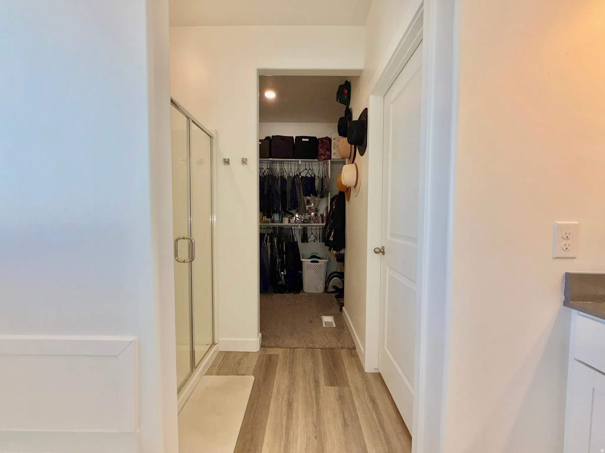 Full bathroom with a walk in closet, vanity, a shower stall, and light wood-type flooring