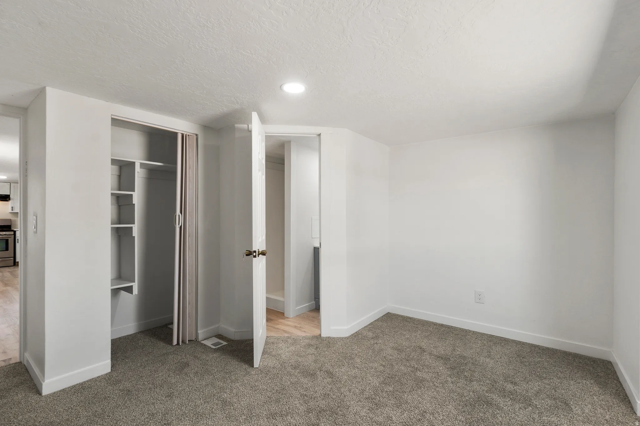 Unfurnished bedroom with light carpet, a textured ceiling, a closet, and recessed lighting