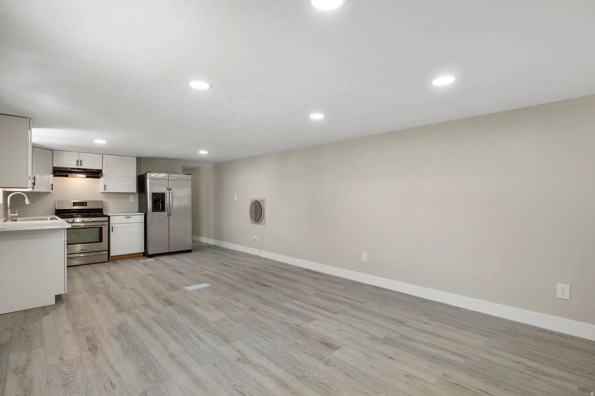 Kitchen featuring white cabinetry, stainless steel appliances, light countertops, light wood-style floors, and recessed lighting