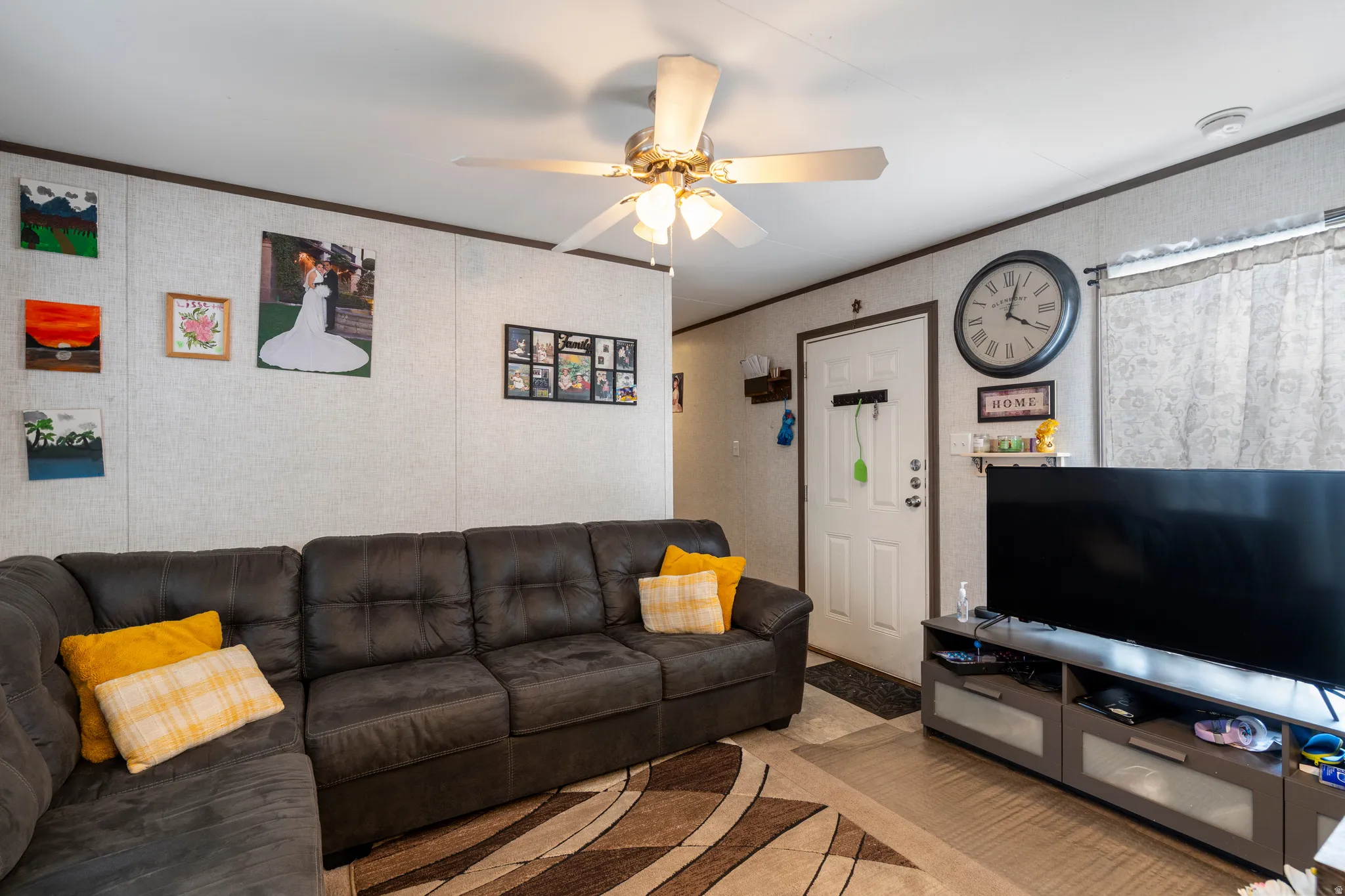 Carpeted living room featuring crown molding and a ceiling fan