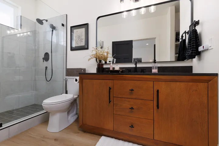 Bathroom featuring vanity, a tile shower, and light wood finished floors