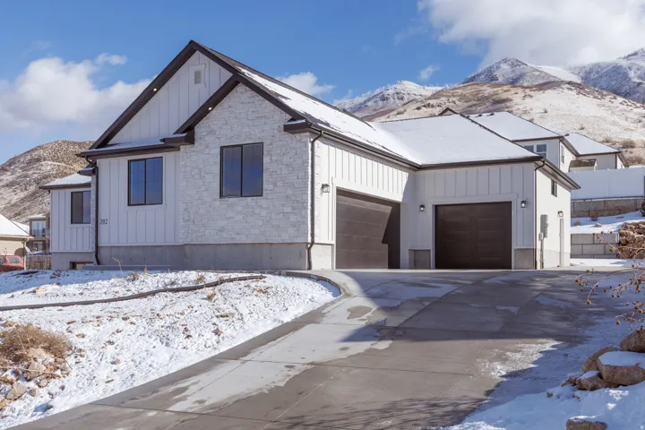 Modern farmhouse style home featuring a mountain view, board and batten siding, stone siding, an attached garage, and concrete driveway