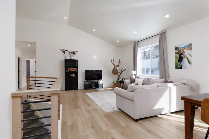 Living room with light wood-style floors, lofted ceiling, and recessed lighting