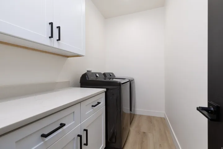 Laundry room featuring light wood-style floors, cabinet space, and washing machine and clothes dryer