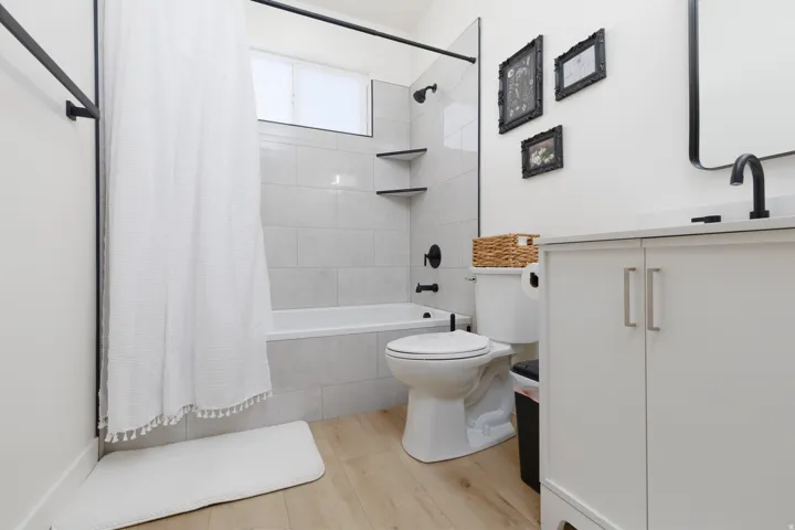 Full bathroom with tiled shower / bath, vanity, and light wood-type flooring