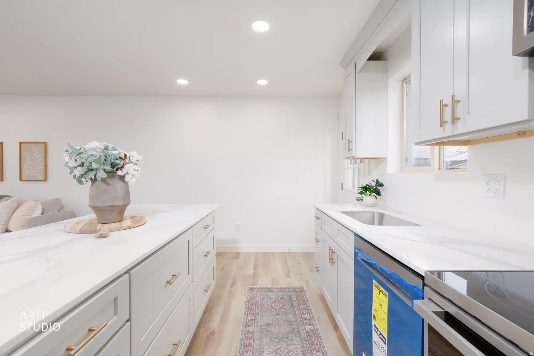 Kitchen with white cabinets, stainless steel appliances, light stone countertops, and recessed lighting