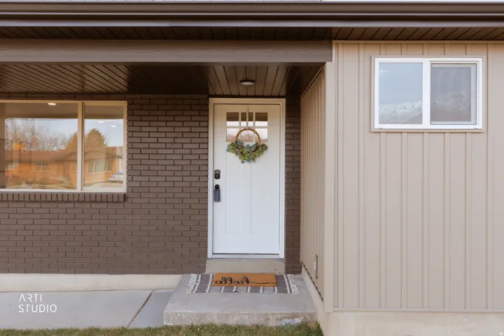 Entrance to property featuring board and batten siding and brick siding
