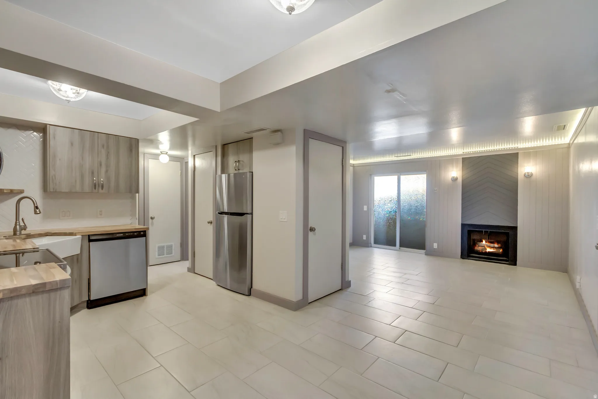 Kitchen featuring stainless steel appliances, a fireplace, open floor plan, grey cabinetry, and butcher block countertops