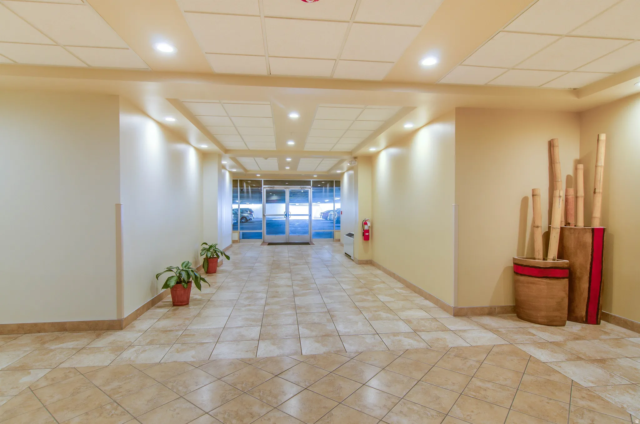 Corridor featuring a drop ceiling, recessed lighting, and light tile patterned floors