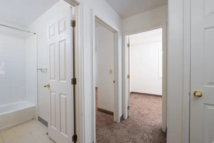 Hallway with baseboards and light colored carpet