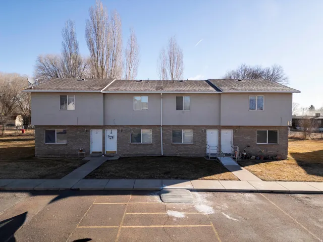 Back of property with brick siding, stucco siding, and a shingled roof