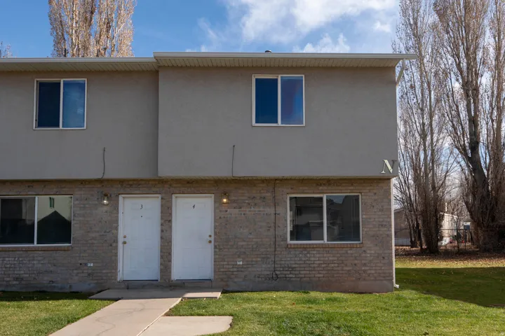 View of front of home featuring stucco siding, a front lawn, and brick siding