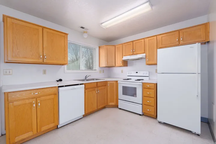 Kitchen featuring white appliances, light countertops, light flooring, and under cabinet range hood