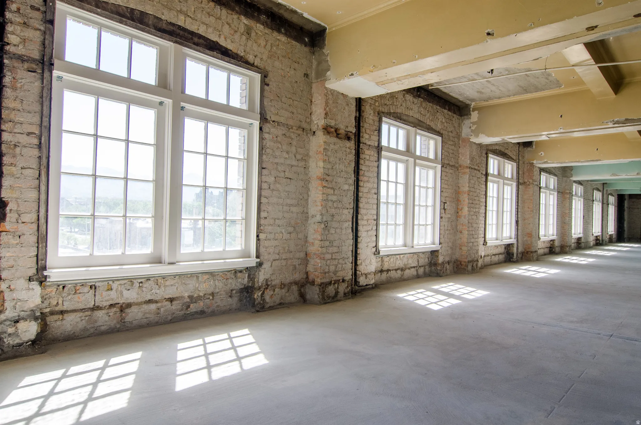 Unfurnished room featuring concrete floors and brick wall