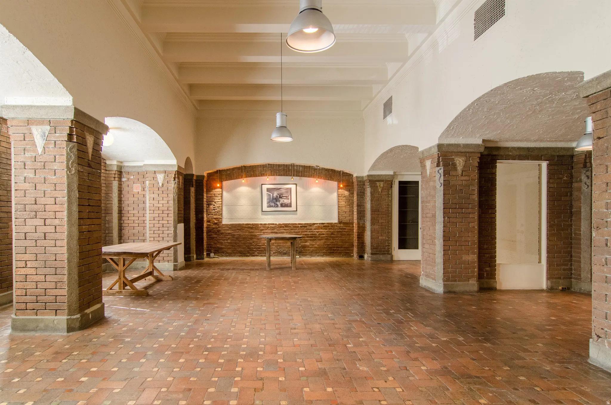 Lobby with brick wall, a towering ceiling, and beamed ceiling