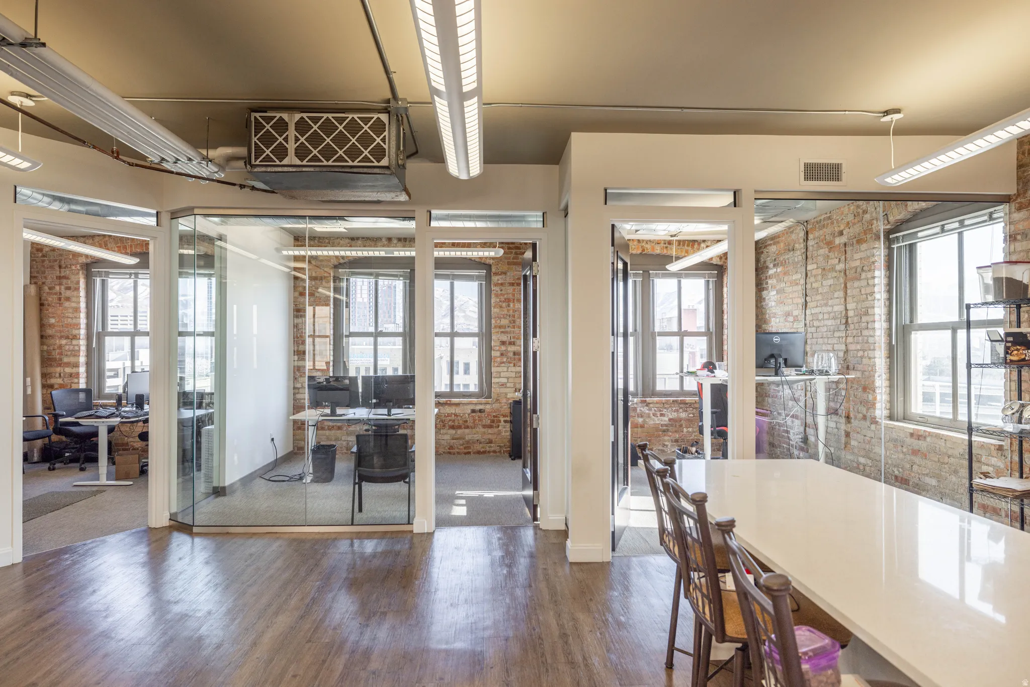 Dining room with brick wall, a desk, dark wood finished floors, and healthy amount of natural light