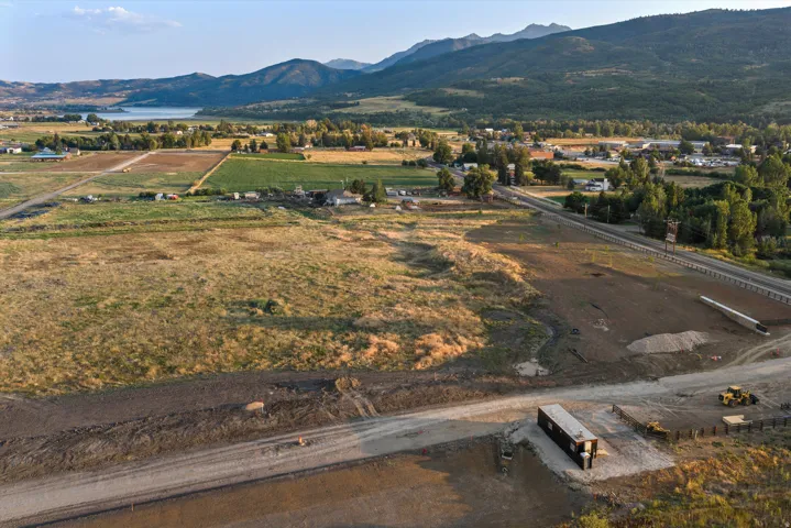 Expansive undeveloped land featuring a cleared section, road frontage, and distant mountains
