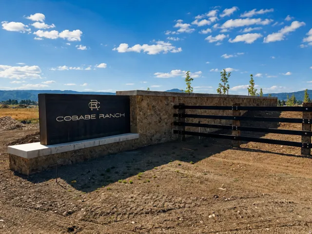 Stone and wood-finish entry monument with a black horizontal fence