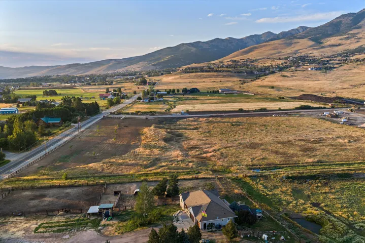 Sprawling rural property featuring a substantial residence set on expansive acreage with mature landscaping, irrigated agricultural fields, and direct highway access