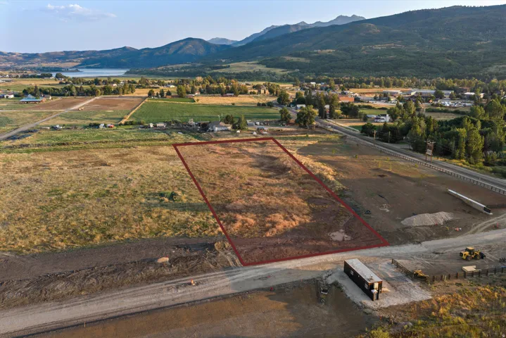 Expansive agricultural land parcel featuring approximately 5+ acres of cleared and prepared ground, bordered by modern infrastructure including a paved roadway with direct access and established utility corridors