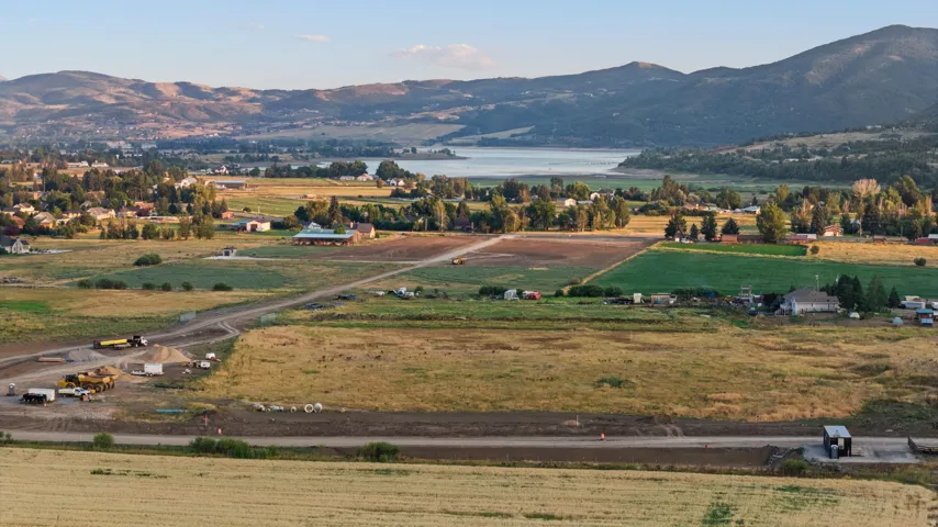 Expansive agricultural property featuring rolling pastureland, established tree lines, and distant mountain backdrop