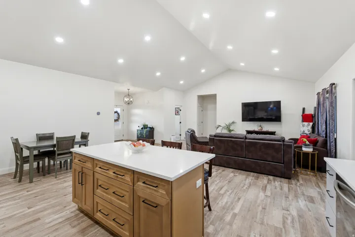 Kitchen with light wood finished floors, brown cabinetry, a kitchen island, a kitchen bar, and open floor plan