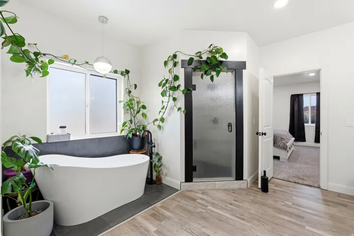 Ensuite bathroom with light wood-style floors, a freestanding bath, a shower stall, and recessed lighting