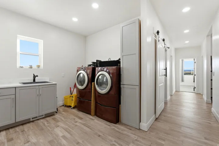 Laundry area featuring a barn door, light wood-type flooring, recessed lighting, separate washer and dryer, and cabinet space