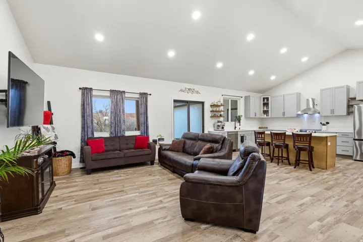 Living room with high vaulted ceiling, light wood-style flooring, and recessed lighting
