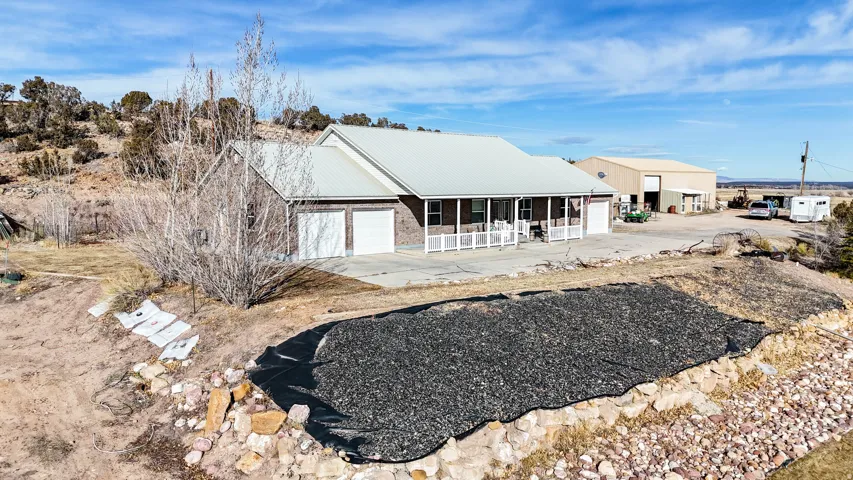 View of front of house featuring concrete driveway, an attached garage, a metal roof, and a patio area