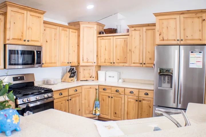 Kitchen with light brown cabinetry, appliances with stainless steel finishes, light stone counters, and recessed lighting