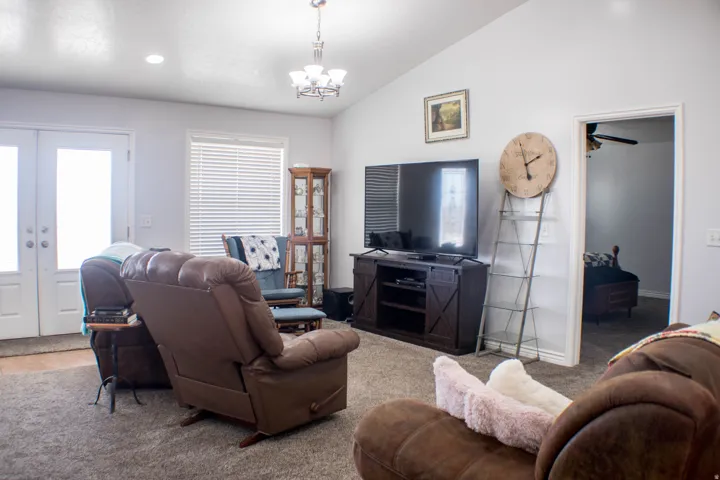 Living room featuring french doors, carpet, lofted ceiling, a chandelier, and recessed lighting