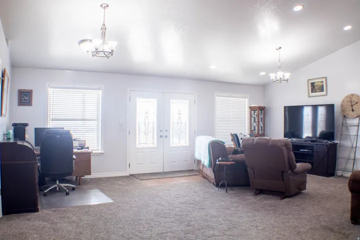 Carpeted living room featuring a chandelier, a desk, vaulted ceiling, french doors, and recessed lighting