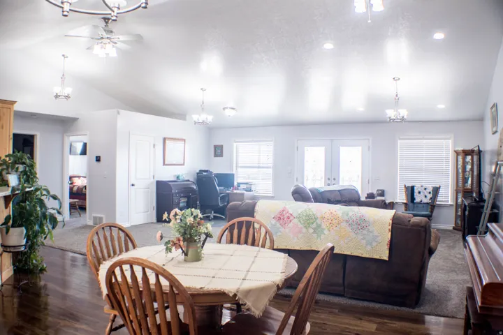 Dining space featuring a chandelier, dark wood-type flooring, vaulted ceiling, ceiling fan, and french doors