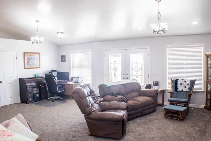 Living area with a chandelier, an office area, carpet floors, and french doors